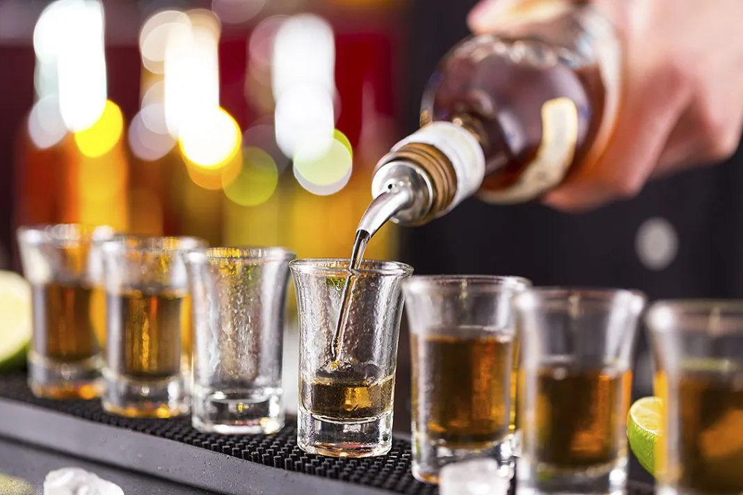 Barman pouring hard spirit into glasses