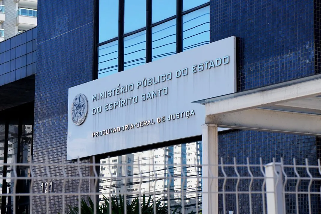 Fachada do Mistério Público Estadual. Ela é azul, com vidros no meio. Tem uma placa grande branca e ferros também brancos na entrada