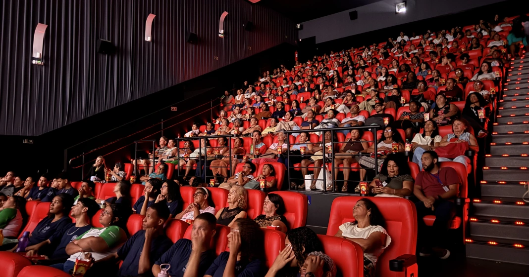 sala de cinema com cadeiras vermelhas, cheia de pessoas para assistir ao documentário Ato Final