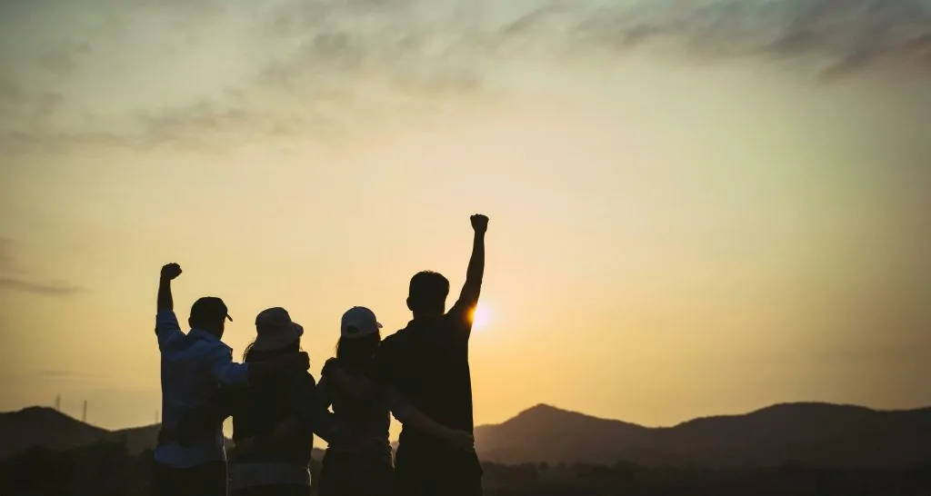 Homens e mulheres reunidos em celebração no pôr do sol (Feminismo e cristianismo podem caminhar juntos?)