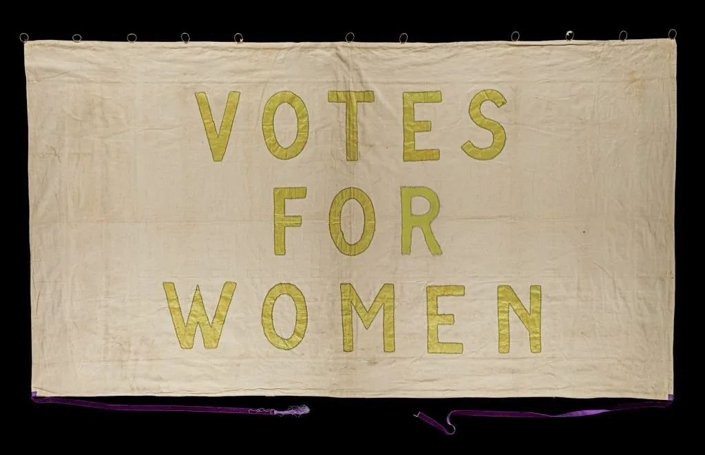 Faixa histórica do movimento sufragista com a frase Votes for Women (Feminismo e cristianismo podem caminhar juntos?)