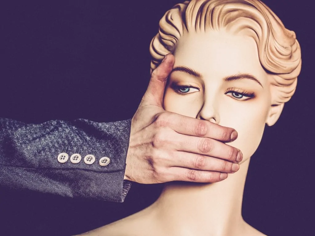 Mãos de um homem tampam a boca de uma mulher (Feminismo e cristianismo podem caminhar juntos?)