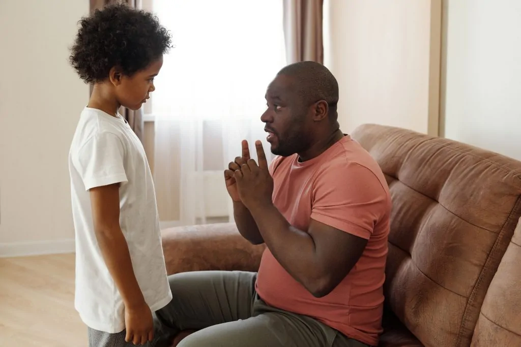 Pai conversa atentamente com o filho dentro de casa