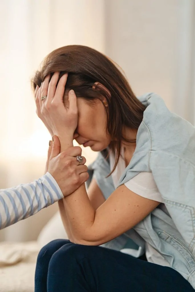 Mulher oferece apoio emocional e segura as mãos de uma amiga em sofrimento.